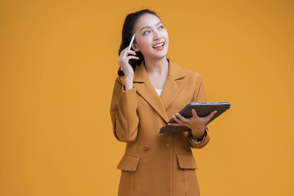 Casual smart asian female business woman hand using tablet business management schedule smiling confident cheerful facial expression studio shot yellow backgroundthinking asian woman in formal cloth