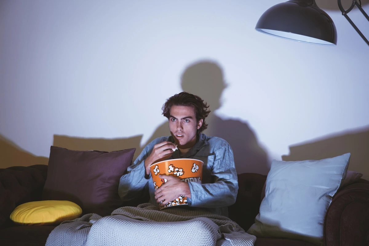 man watching tv or movie with popcorn