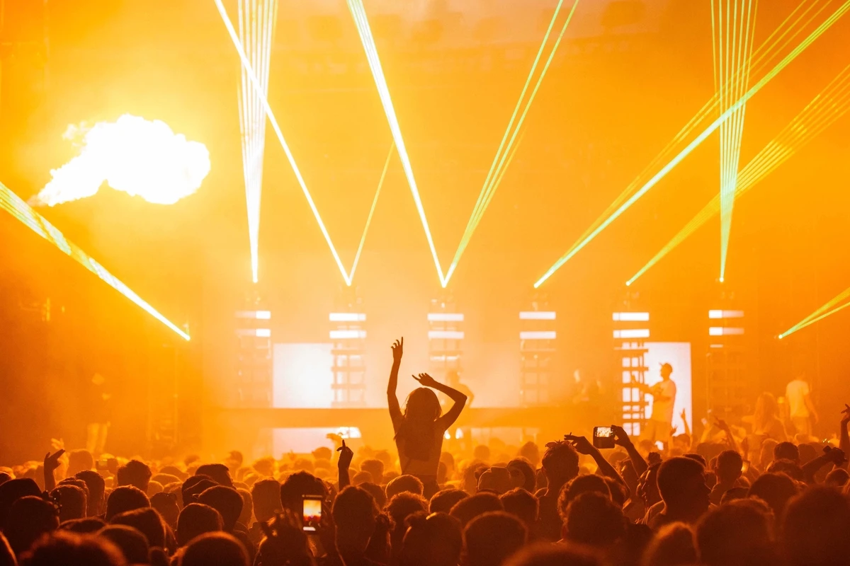 Beautiful shot of a live concert performance with a yellow light show and a big crowd cheering