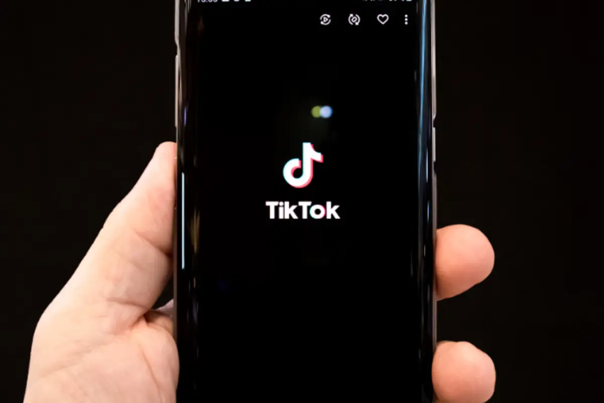 tangan menggenggam handphone yang menampilkan layar logo tiktok